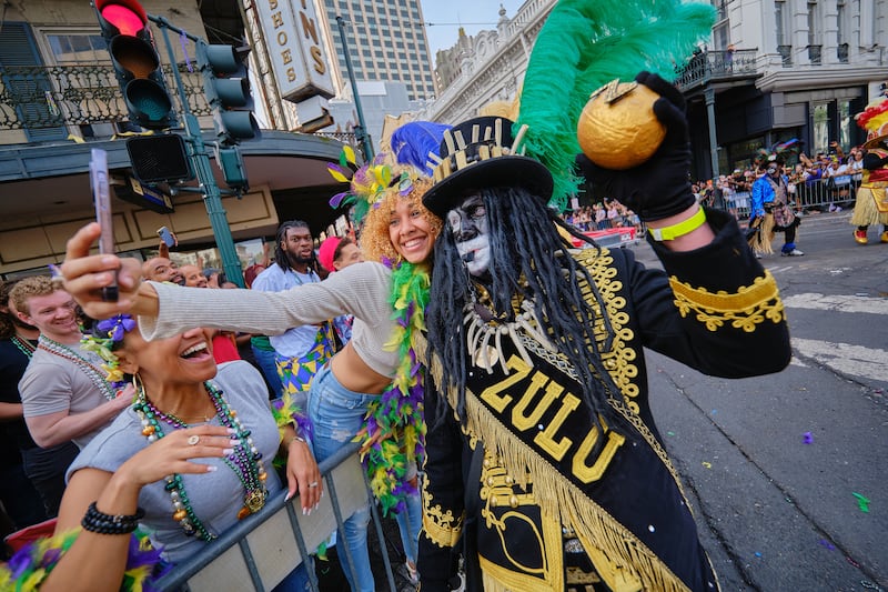 A member of the crowd poses for a photo with a member of the Krewe of Zulu. EPA