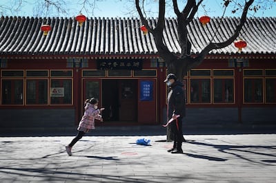 A girl wearing a face mask jumps as she plays with her father in a park in Beijing on March 14, 2020.  China reported 11 new infections of the coronavirus on March 14, and for the first time since the start of the epidemic the majority of them were imported cases from overseas. 
 / AFP / WANG ZHAO
