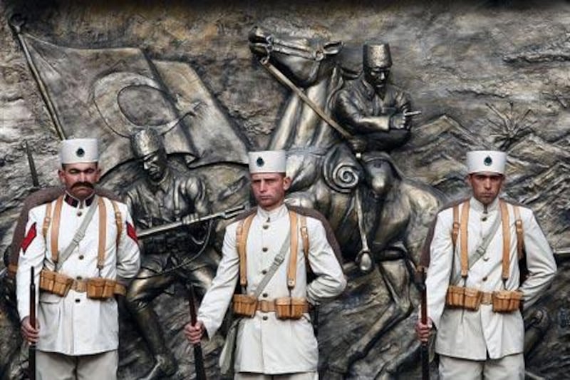 Soldiers dressed in uniforms of the Turkish War of Independence stand in front of a tribute to Mustafa Kemal Ataturk.
