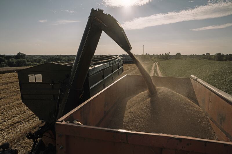 A combine harvester unloads grain into a trailer on Monday during the summer wheat harvest in Ukraine. Bloomberg