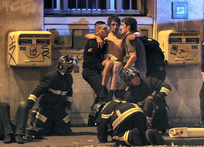 ATTENTION EDITORS - VISUAL COVERAGE OF SCENES OF INJURY OR DEATH  French fire brigade members aid an injured individual near the Bataclan concert hall following fatal shootings in Paris, France, November 13, 2015. At least 30 people were killed in attacks in Paris and a hostage situation was under way at a concert hall in the French capital, French media reported on Friday.  REUTERS/Christian Hartmann      TPX IMAGES OF THE DAY