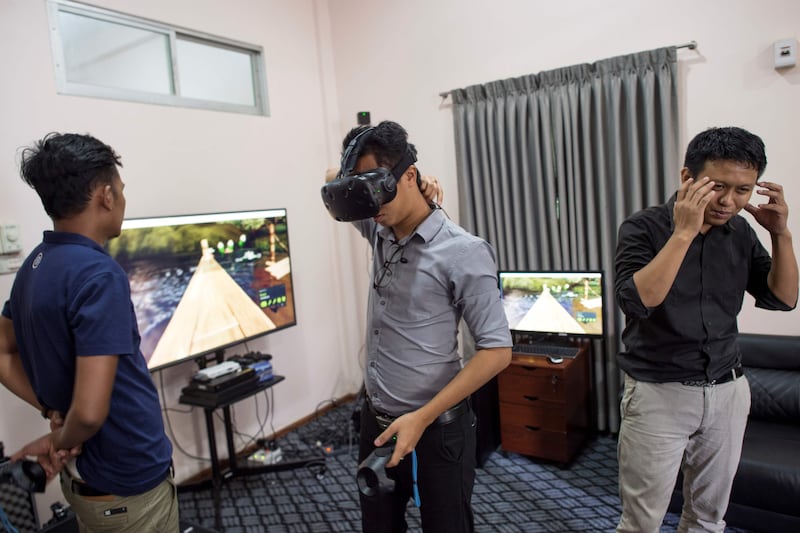 In this photograph taken on August 11, 2017, Nyi Lin Seck (R) speaks about virtual reality technology to curious people wanting to learn more about it during a one day open house at his office in Yangon.
Few countries in the world have experienced such rapid discovery of technology than Myanmar which has leapfrogged from the analogue to digital era in just a few years. / AFP PHOTO / Ye Aung Thu / TO GO WITH Myanmar-technology-history-education-computers,FEATURE by Phyo Hein KYAW