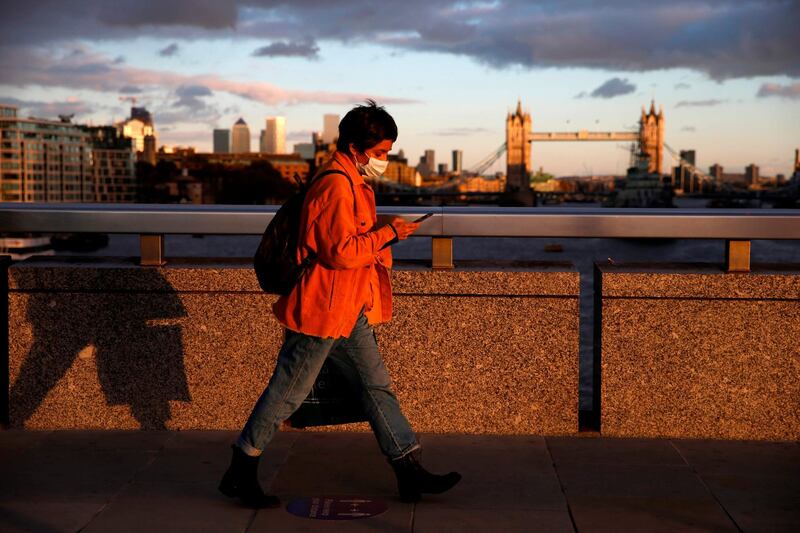 A pedestrian wearing a mask crosses London Bridge with Tower Bridge in the background in central London. England is preparing to head into a second coronavirus lockdown. AFP