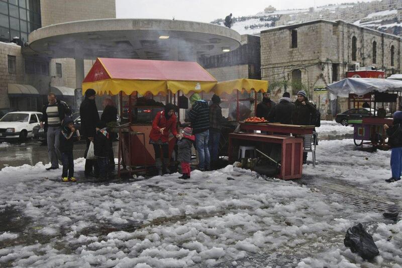 Palestinians eat in West Bank’s snowcapped town of Nablus on Saturday. Schools in the West Bank remain closed Sunday. Nasser Ishtayeh / AP Photo