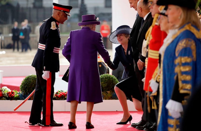 Britain's Queen Elizabeth II, centre, shakes hands with Britain's Prime Minister Theresa May, right, on the dias as they take their places for a ceremonial welcome for King Willem-Alexander and Queen Maxima of the Netherlands on Horse Guards Parade in London at the start of the Dutch King and Queen's two-day state visit. Matt Dunham / AFP