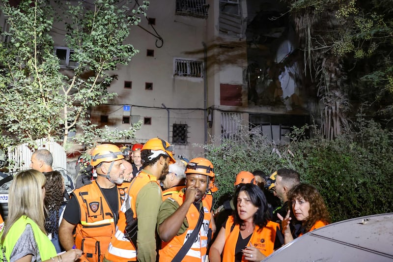 Rescuers in front of an apartment building hit by a rocket in the Israeli city of Rishon LeZion. AFP