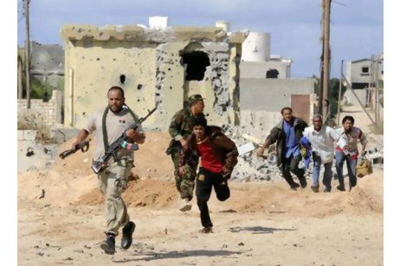 Libya's National Transitional Council fighters escort civilians fleeing Sirte during heavy fighting Monday.