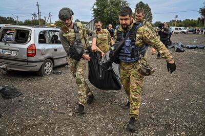 Ukrainian servicemen carry a plastic bags which contains a body of one of the victims. AFP