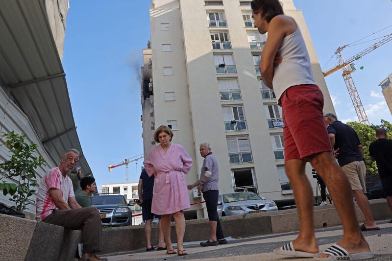 Residents gather outside a damaged building in Tel Aviv following a rocket attack from the Gaza Strip into Israel. AFP