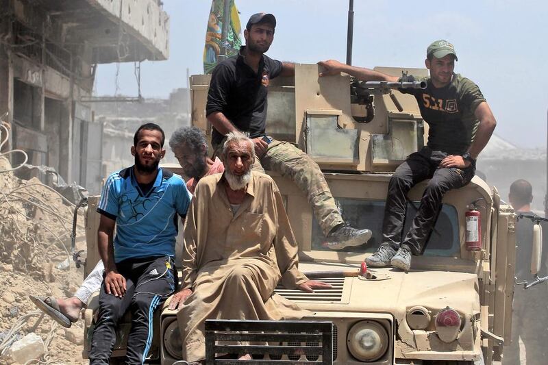 Iraqi civilians and forces members on an armoured vehicle following a suicide bomber attack as people were escaping the Old City of Mosul, on June 23, 2017. Ahmad Al Rubaye / AFP

