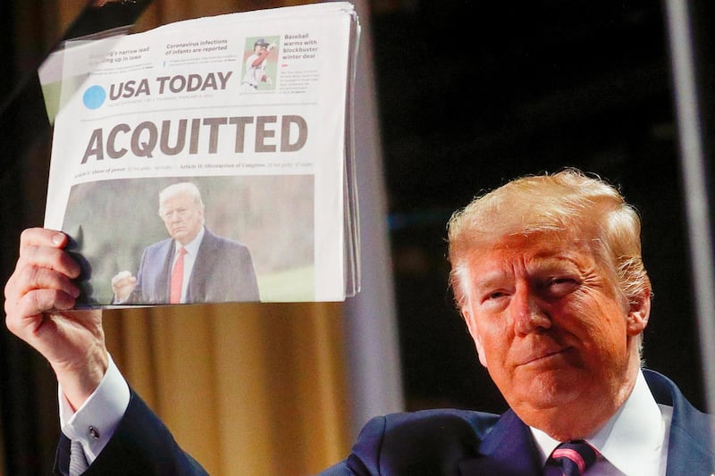 US President Donald Trump holds up a copy of USA Today's front page showing news of his acquittal in his Senate impeachment trial on February 6, 2020. Reuters