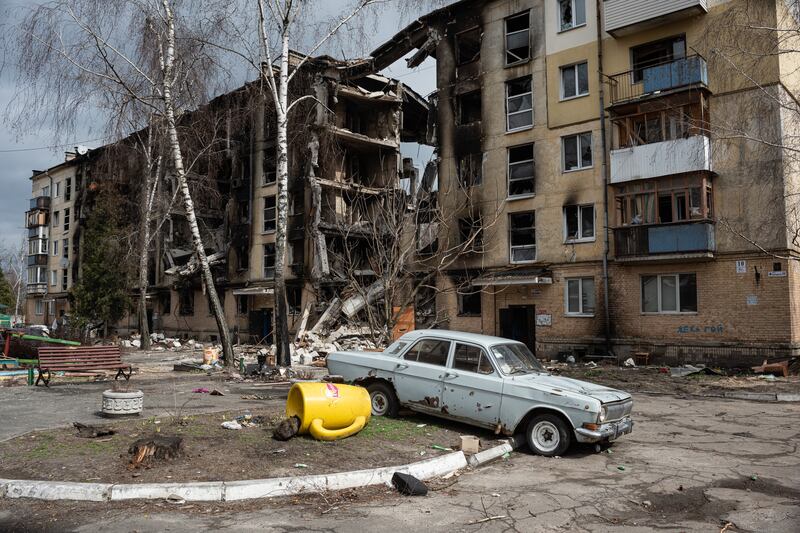 A damaged car is seen next to a heavily damaged apartment building in Hostomel, Ukraine. Getty Images