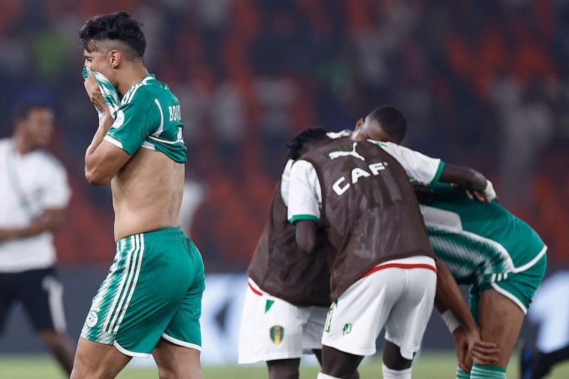 Algeria's Baghdad Bounedjah leaves the field dejected as Mauritania celebrate their win. AFP
