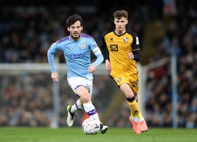 MANCHESTER, ENGLAND - JANUARY 04: David Silva of Manchester City runs with the ball under pressure from Scott Burgess of Port Vale during the FA Cup Third Round match between Manchester City and Port Vale at Etihad Stadium on January 04, 2020 in Manchester, England. (Photo by Alex Livesey/Getty Images)