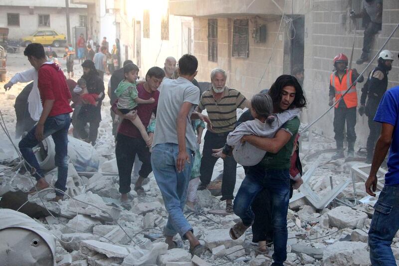 Syrian men carry the injured amid the rubble of buildings destroyed by an air strike on the rebel-held northwestern city of Idlib on September 29, 2016 The Syrian Observatory for Human Rights said at least five air strikes hit various areas of the city. Omar Haj Kadour / Agence France-Presse