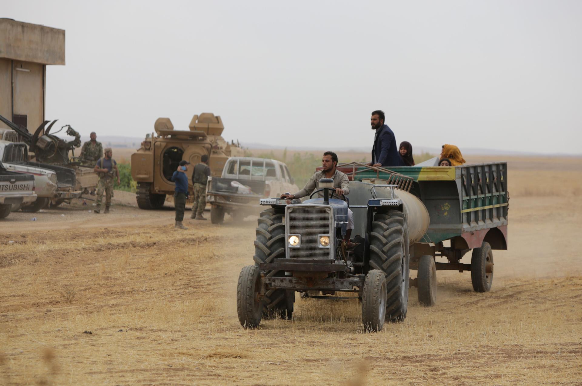 Syrians ride in the back of a farmer's truck as they flee villages where fighting continues in the countryside of Tal Abyad. AFP