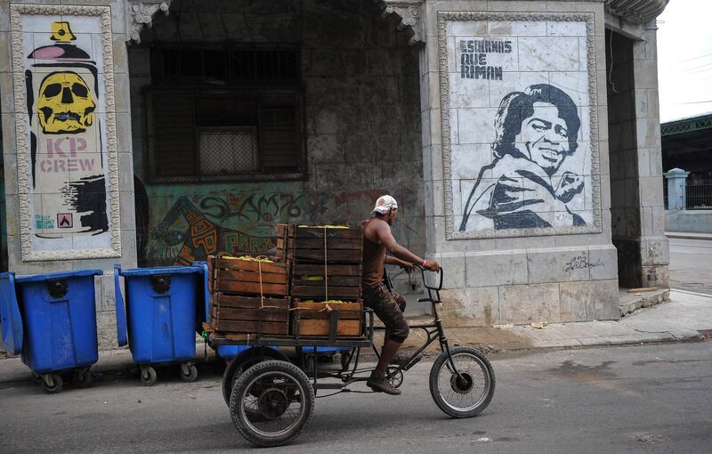 A Cuban passes on his bycicle by a graffiti of street art in Havana, on July 12, 2017. / AFP PHOTO / YAMIL LAGE