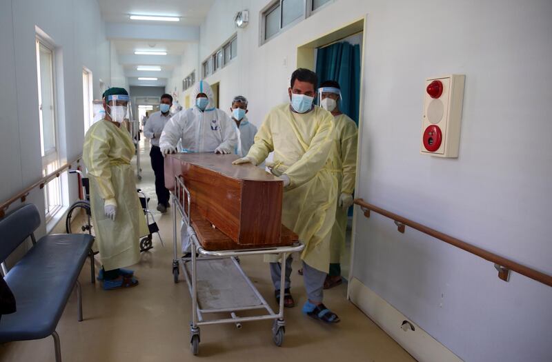 Afghan health workers carry the body of a man who died from Covid-19.