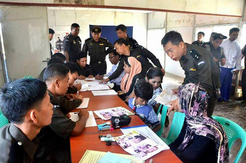 In this April 14, 2018, photo provided by  Myanmar Government Information Committee, Myanmar immigration officials examine documents and photographs with a Rohingya family of five at a receiving center in Taung Pyo, Letwe, northern Rakhine state.  Myanmar has accepted what appears to be the first five among some 700,000 Rohingya Muslim refugees who fled military-led violence against the minority group, even though the U.N. says it is not yet safe for them to return home.  (Myanmar Government Information Committee via AP)