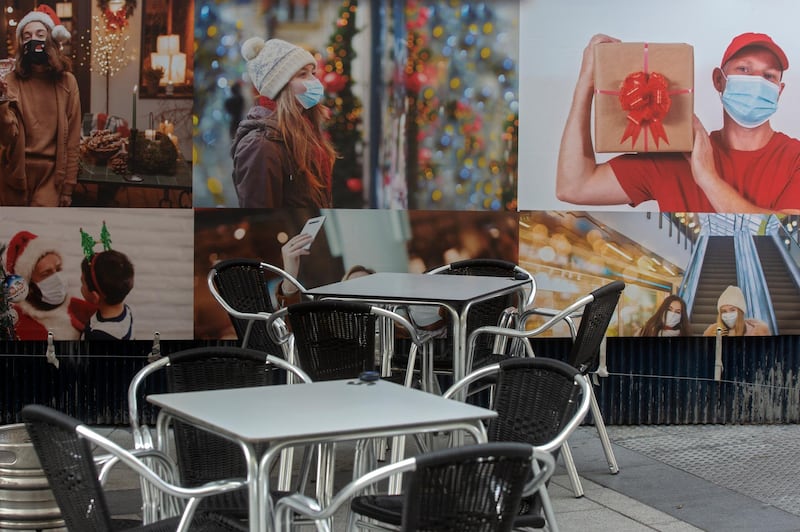 Empty tables and chairs in a terrace bar sit by posters of people wearing face masks in Madrid, Spain. AP