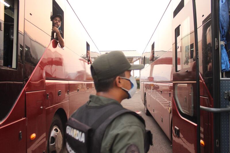 A member of the military stands guard as Venezuelans board a bus back to their homes after being quarantined at the Colombian border in Urena, Tachira, Venezuela. EPA
