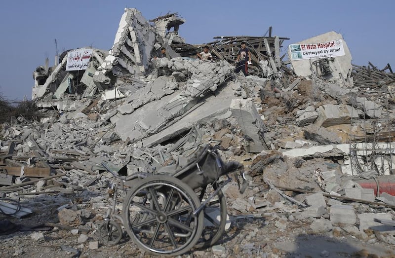 Palestinians stand atop the ruins of the headquarters of El Wafa rehabilitation hospital. Ibraheem Abu Mustafa / Reuters