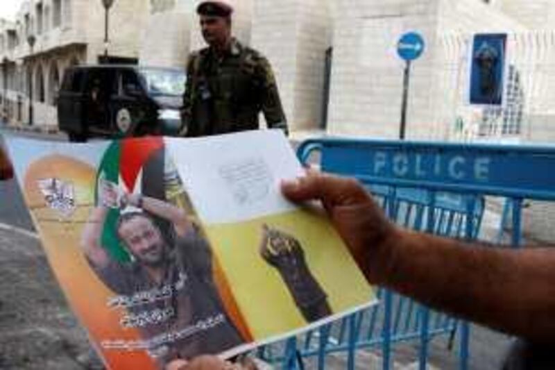 A member of the Palestinian security forces holds a placard depicting Marwan Barghouthi outside the Fatah congress in the West Bank town of Bethlehem August 11, 2009. Barghouthi, who is serving life in an Israeli jail on charges of organising the killing of Jews, was elected to a top post in Palestinian President Mahmoud Abbas's Fatah group on Tuesday, initial results showed. REUTERS/Nayef Hashlamoun (WEST BANK POLITICS ELECTIONS) *** Local Caption ***  JER12_PALESTINIANS-_0811_11.JPG *** Local Caption ***  JER12_PALESTINIANS-_0811_11.JPG