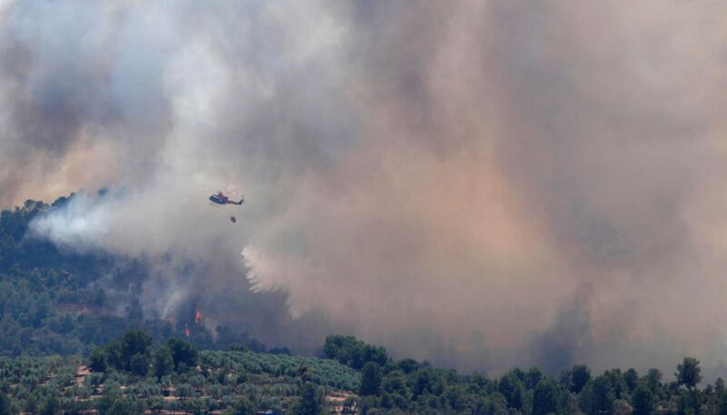A helicopter drops water over a fire during a forest fire near Bovera, west of Tarragona, Spain on Thursday. Reuters