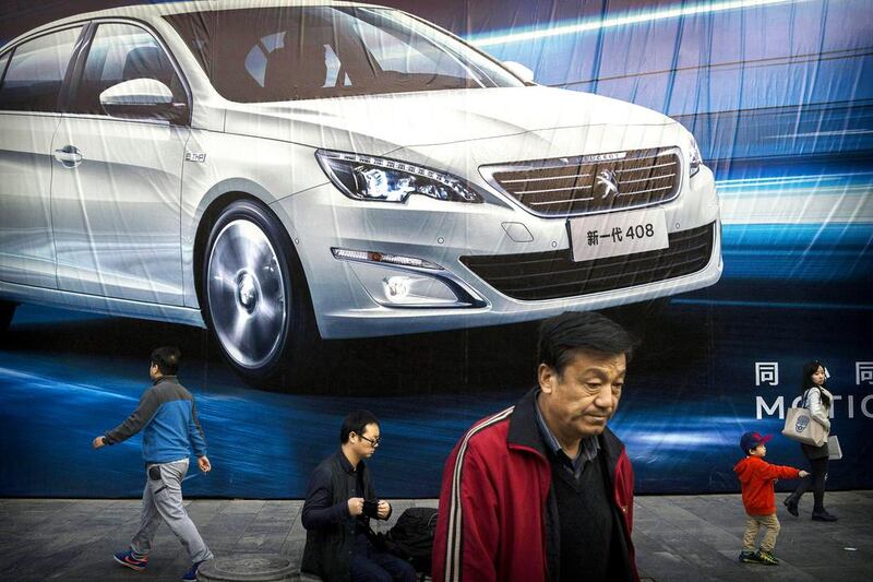 People walk past an advertisement for a foreign auto maker on a wall on October 27, 2014 in Beijing, China. Economic data showed that the country's growth dropped to a five year low and is slowing due to a decrease in exports and property development in recent months, reports say. Kevin Frayer / Getty Images