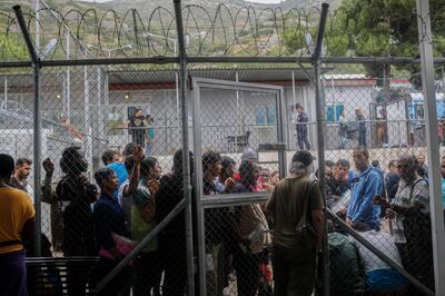 In this Wednesday, Sept. 25, 2019 photo, people wait outside the information office at a refugee and migrant camp of the Greek island of Samos. Greece's conservative government announced Wednesday Nov. 20, 2019, plans to overhaul the country's migration management system, and replacing existing camps on the islands with detention facilities and moving and 20,000 asylum seekers to the mainland over the next few weeks. (AP Photo/Petros Giannakouris)