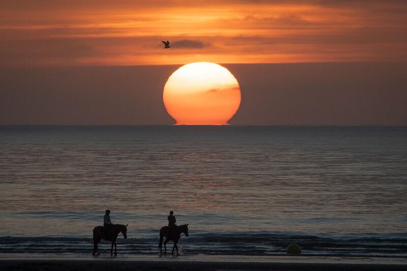 Riders and their horses walk across the sands as the sun sets on the beach at Deauville, north-west France,  during the 46th Deauville US film festival. AFP