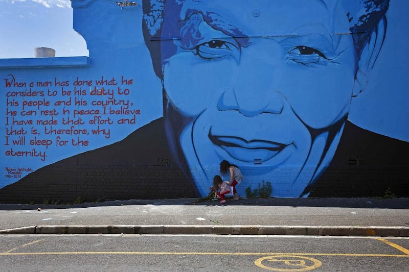 Kitty Harris, 5, and her sister India, 8, lay bouquets of flowers for the late former South African President Nelson Mandela at a wall mural in Cape Town. Reuters