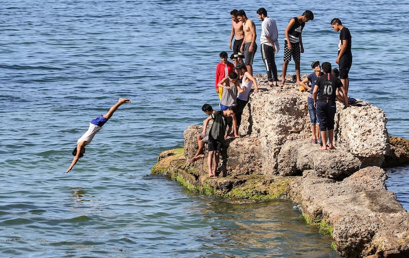 A boy dives as youths cool off by the water at a beach off the Mediterranean coast of Libya's capital Tripoli, despite a lockdown against coronavirus pandemic. AFP