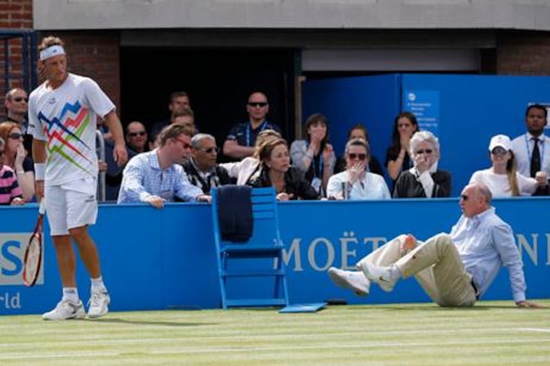 Argentina's David Nalbandian, left, looks on after causing an injury to the line judge, right, and is disqualified during the Queen's Club grass court championships final tennis match against Croatia's Marin Cilic, London, Sunday, June 17, 2012. Nalbandian kicked the small barrier surrounding the line judge in anger. A piece of the barrier then hit the line judge, causing bleeding on his left shin. (AP Photo/Sang Tan) 