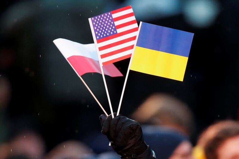 A man holds Ukrainian, Polish and US  flags. Reuters