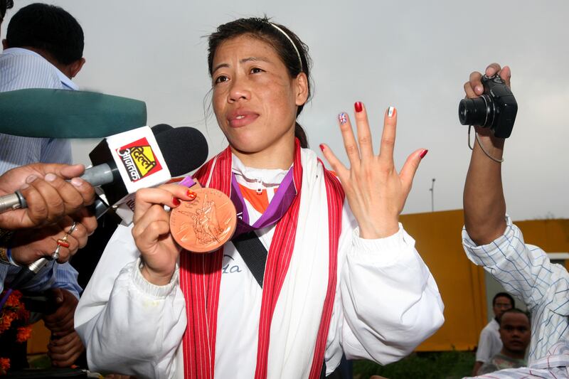 NEW DELHI, INDIA -  AUGUST 14 : London Olympics bronze medalist woman boxer Mary Kom is surrounded with her fans and media persons on her arrival at IGI Airport. Woman boxer Mary Kom was feted as India's latest sporting hero after the mother-of-two won a bronze medal at the London Olympics. (Photo by K Asif/India Today Group/Getty Images)