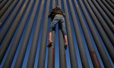 A migrant, part of a caravan of thousands from Central America trying to reach the United States, climbs the border fence between Mexico and the United States, in Tijuana, Mexico, November 18, 2018. REUTERS/Hannah McKay       TPX IMAGES OF THE DAY