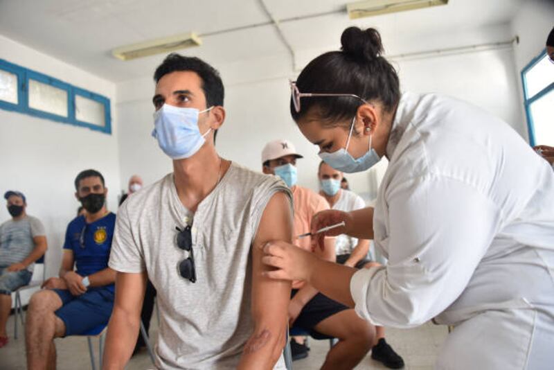 A health worker gives a dose of the Moderna coronavirus vaccine to a man at an inoculation centre in a school building in Tunis.
