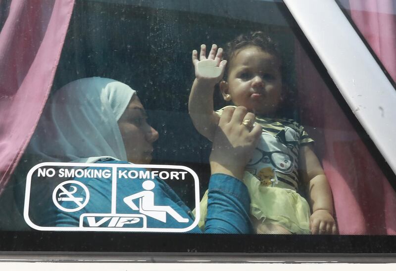 Syrian refugee Umm Luay, 30, sits with her child inside a bus on September 17, 2018  she return with her family to Syrian after living as refugees in Lebanon for years. In 2012, Rawad Kurdi and his 35 relatives were forced to flee their hometown of Babila southeast of Damascus after fighting broke out between rebels and government forces. 
They came to Lebanon. Three years later, some of the elderly family members including Rawad's father Ahmad returned to Syria, and more have hit the road home since.

 / AFP / ANWAR AMRO
