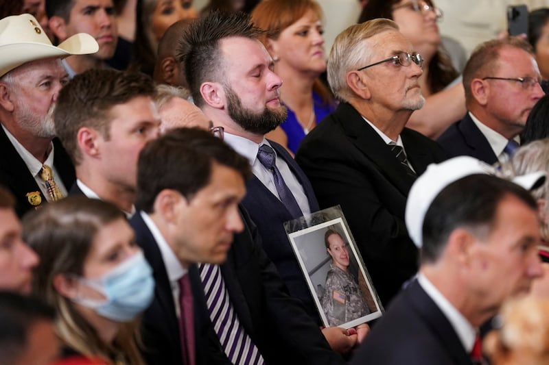 Mr Benson holds up a picture of his deceased wife Katie, a former US army medic, during the signing ceremony. Reuters