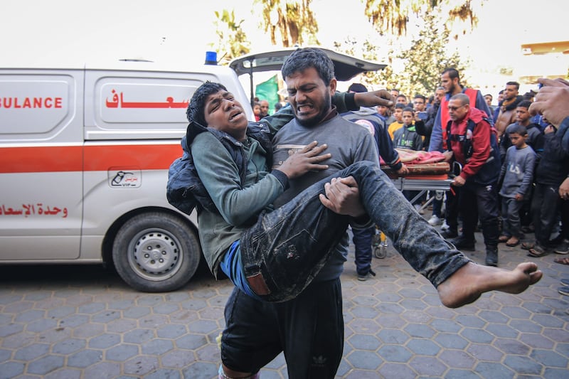 A man carried an injured Palestinian man to Al Aqsa Hospital after an Israeli air strike in Deir Al-Balah in southern Gaza. Bloomberg