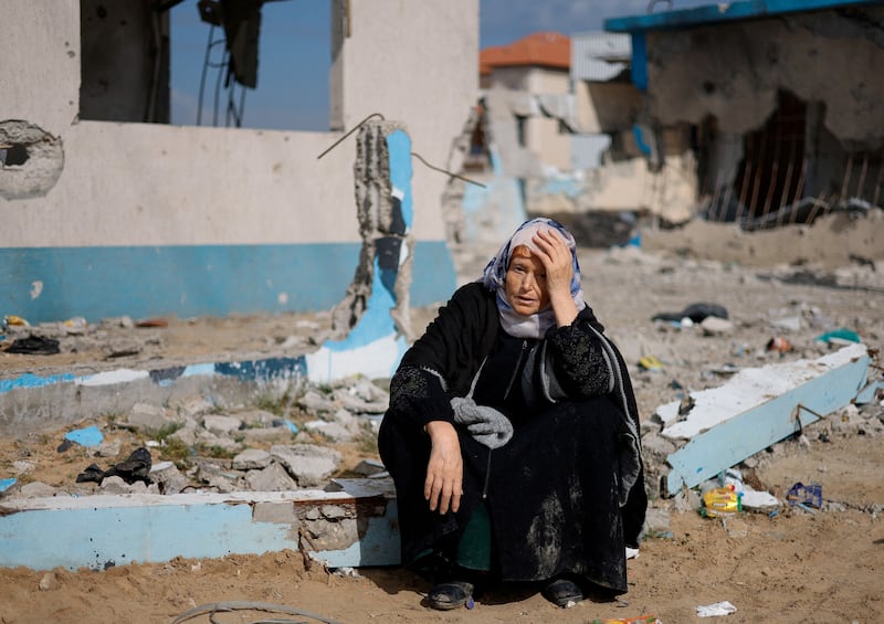 A woman sits next to a damaged building in Rafah, southern Gaza, after being evacuated from Nasser Hospital in Khan Younis. Reuters