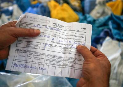 A Palestinian postal worker holds in his hands a bill for a parcel dating back to 2015, one of many items of mail that was undelivered for eight years because it was withheld by Israel, at the central international exchange post office in the West Bank city of Jericho on August 14, 2018. - Israel had held the post for years but handed it over to the Palestinian authorities after an agreement. (Photo by ABBAS MOMANI / AFP)