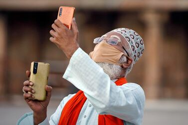 A Muslim man wearing a protective mask uses his mobile phone camera as he tries to spot the new moon that will mark the start of the fasting month of Ramadan, during a nationwide lockdown to slow the spreading of the coronavirus disease (COVID-19), at a mosque in Ahmedabad, India, April 24, 2020. REUTERS/Amit Dave