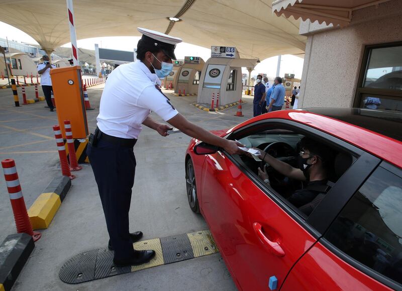 An immigration officer assists an American national in a car as he arrives at a medical checkpoint while crossing from Saudi Arabia into Bahrain. Reuters