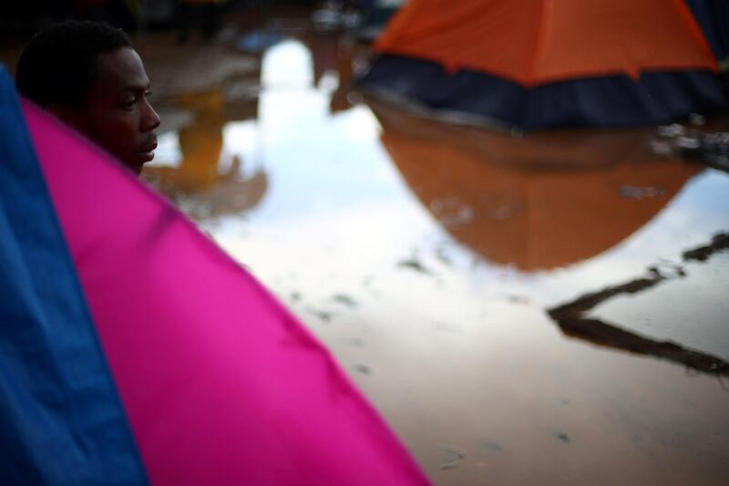 A migrant looks out from his tent after heavy rainfall. Reuters