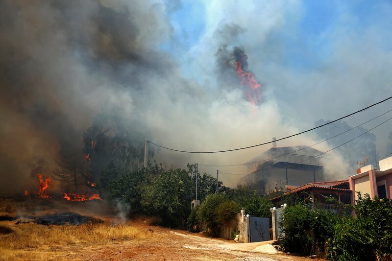 Blazes rage around houses during a wildfire that broke out in the area of Keratea, Greece.