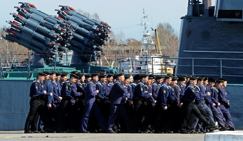 Officers of the Russian naval army march past a small anti-submarine ship at a Navy base in the town of Kronstadt outside St. Petersburg on April 26, 2014. AFP PHOTO / OLGA MALTSEVA (Photo by OLGA MALTSEVA / AFP)