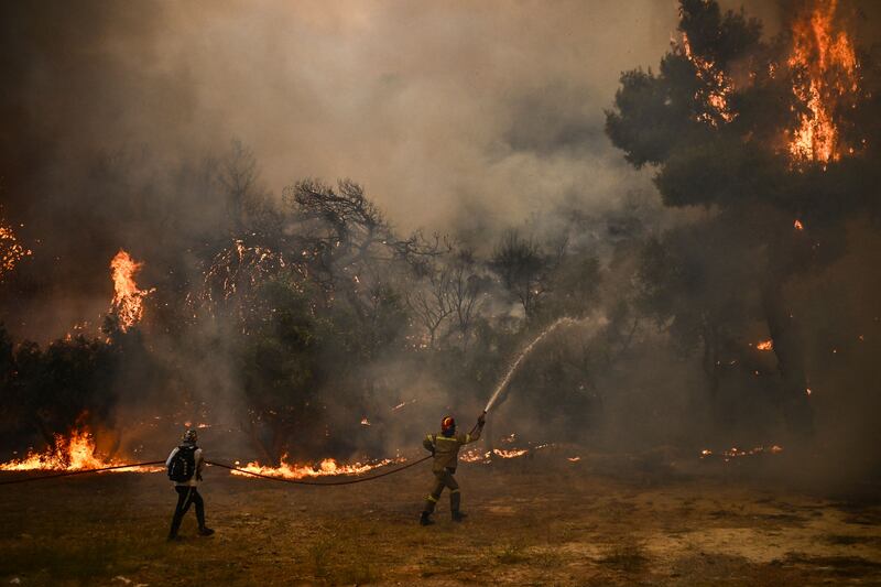 Firefighters dampen the flames in Chasia as wildfire closes in on the Greek capital, parts of which were evacuated. AFP