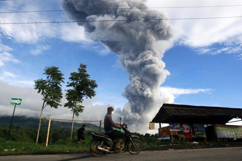 A resident rides his motorcycles as mount Sinabung spews smoke and ashes, at Tiga Serangkai village in Karo, North Sumatra, Indonesia. Dedi Sahputra / EPA